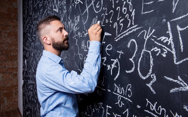 Ein Mann schreibt Formeln auf eine Tafel