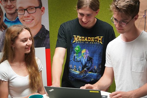 Gruppenfoto von Praktikant*innen des DVZ.SommerBootcamp 2022, wie sie gemeinsam auf einen Laptop schauen