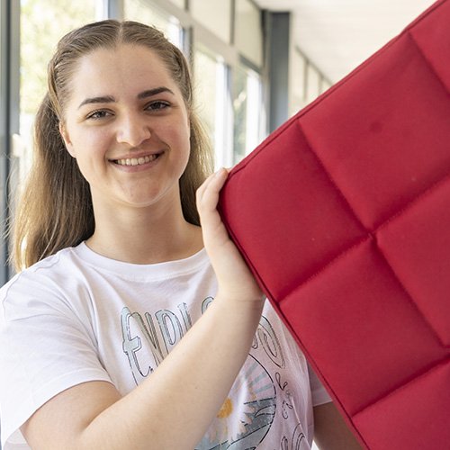 Foto von Dora Konrad, die einen roten Sitzwürfel in der Hand hält