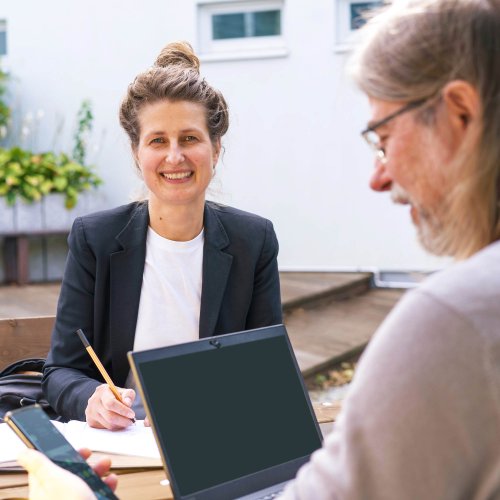 DVZ-Mitarbeiter*innen sitzen im Innenhof und halten ein Meeting ab