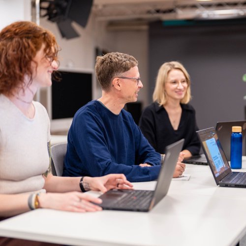 Zwei Frauen und ein Mann sitzen an einem Tisch und unterhalten sich