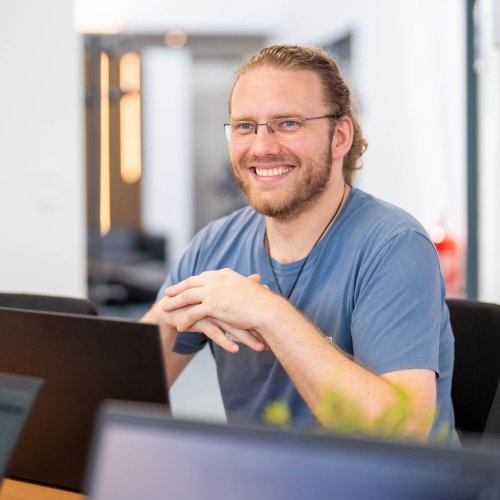 Mann sitzt an einem Laptop und lächelt