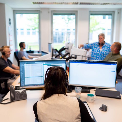 DVZ-Mitarbeiter*innen sitzen in einem großen Büro