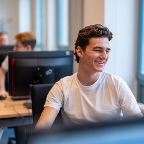 Junger Mann sitzt an einem Laptop