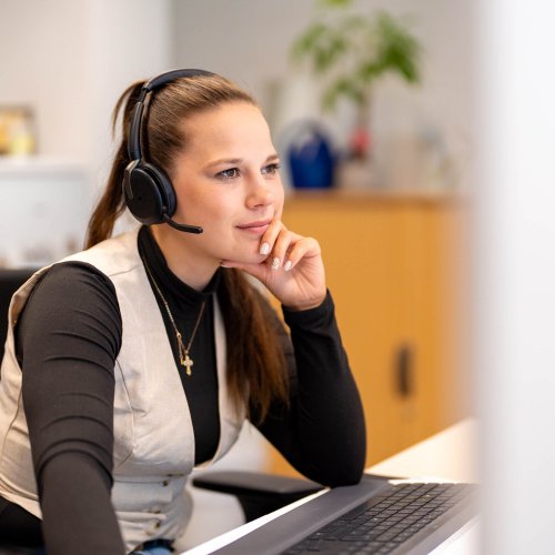 Frau mit Headset sitzt vor einem Computer