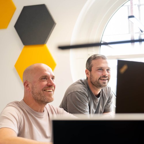 Zwei DVZ-Mitarbeiter, die auf einen Bildschirm schauen