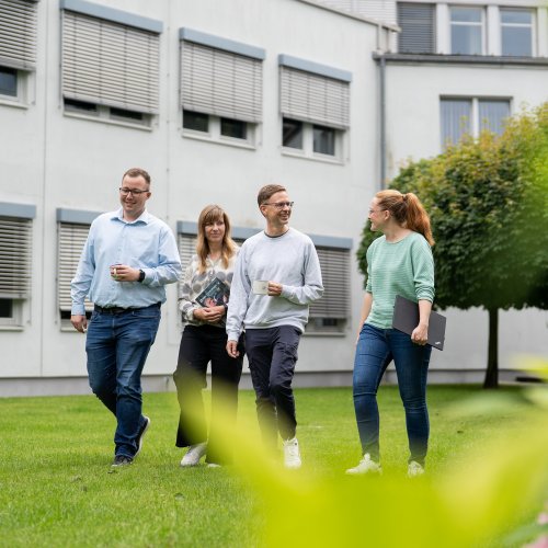 Foto von vier DVZ-Kolleg*innen im Innenhof gehend
