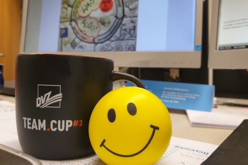 Foto: DVZ-Merchandise (eine Tasse und ein gelber Ball) auf einem Bürotisch