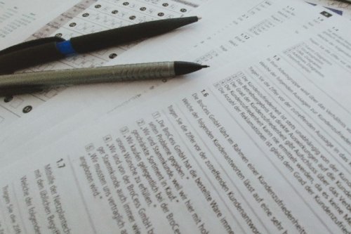 Foto von Klausurblättern und Stiften, die auf einem Tisch liegen