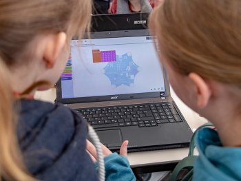 Foto: Zwei Schülerinnen arbeiten an einem Laptop.
